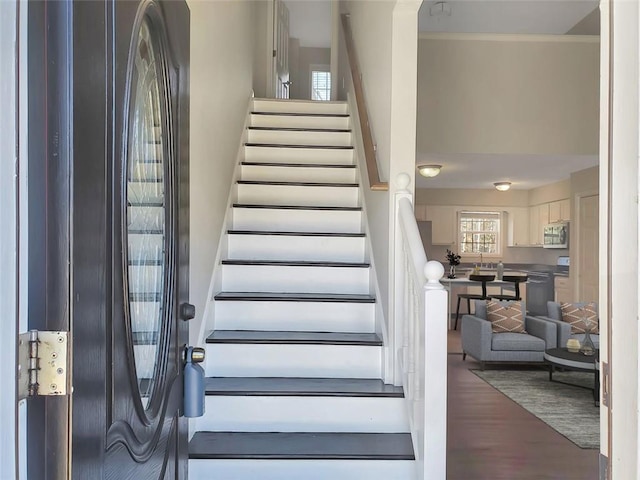 stairway featuring ornamental molding and wood finished floors