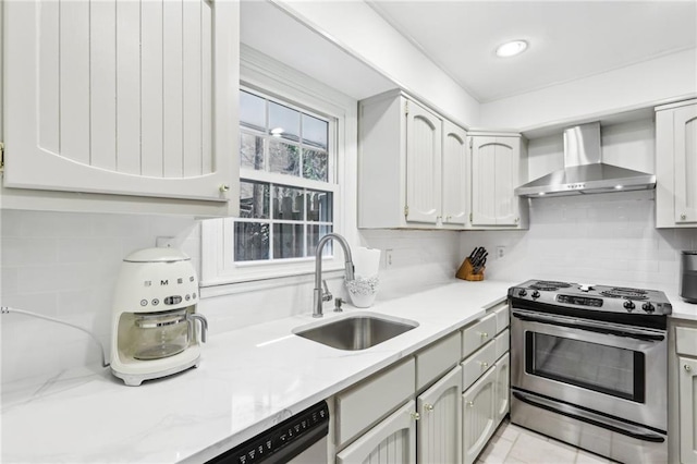 kitchen featuring a sink, light stone counters, tasteful backsplash, appliances with stainless steel finishes, and wall chimney exhaust hood