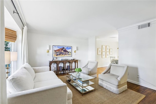 living area with visible vents, crown molding, baseboards, and wood finished floors