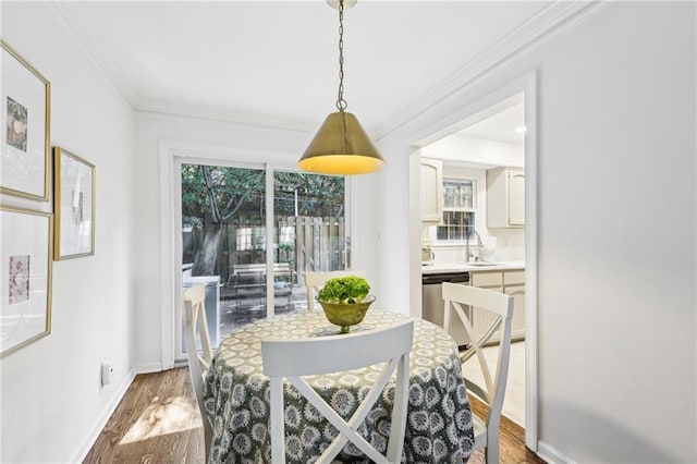 dining room featuring baseboards, light wood-style floors, and ornamental molding