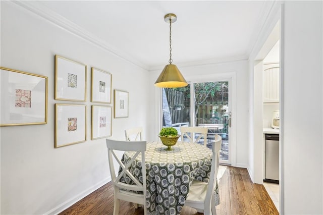 dining space featuring wood finished floors, baseboards, and ornamental molding