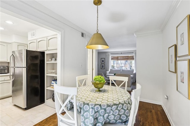 dining space featuring visible vents, light wood-style flooring, crown molding, and baseboards