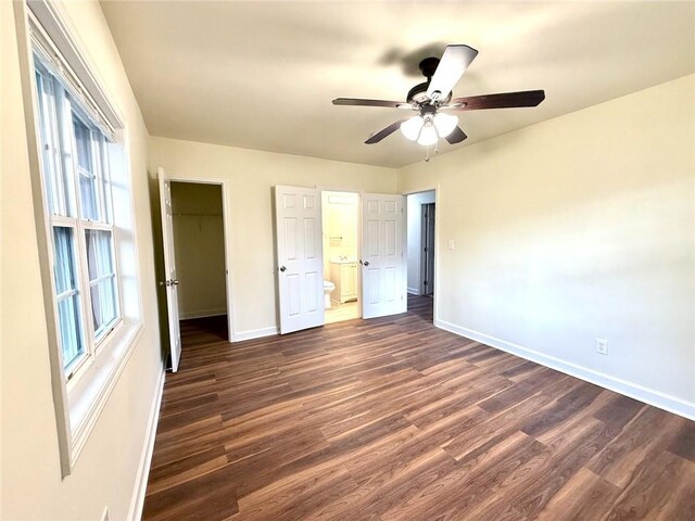 2182 Rosewood Rd, Decatur, GA 30032 - unfurnished bedroom featuring dark wood-style flooring, baseboards, ensuite bathroom, a walk in closet, and ceiling fan