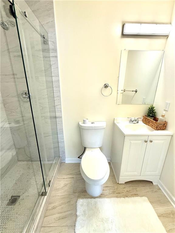 2182 Rosewood Rd, Decatur, GA 30032 - full bath featuring wood finished floors, vanity, baseboards, and a marble finish shower