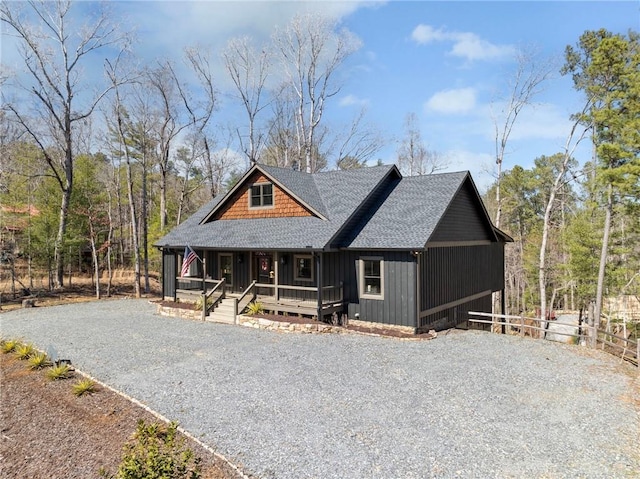 chalet / cabin with board and batten siding, fence, a porch, roof with shingles, and driveway