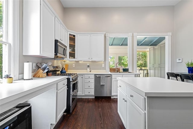 161 N Barton St, Norcross, GA 30071 - kitchen featuring stainless steel appliances, dark wood-style floors, light countertops, white cabinets, and glass insert cabinets