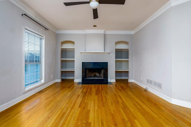 unfurnished living room featuring ceiling fan, hardwood / wood-style floors, built in features, and crown molding