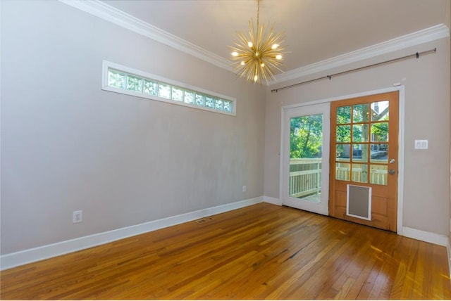 spare room with a notable chandelier, ornamental molding, and hardwood / wood-style flooring