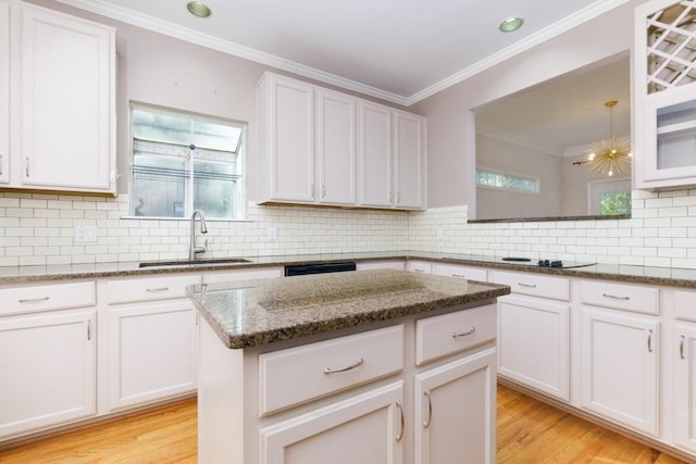 kitchen with white cabinets, sink, stone counters, and a center island