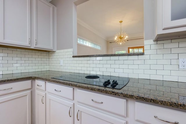 kitchen with white cabinetry, backsplash, black electric cooktop, and hanging light fixtures