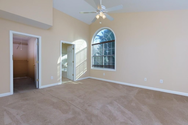 unfurnished bedroom featuring ceiling fan, a walk in closet, a closet, and light carpet