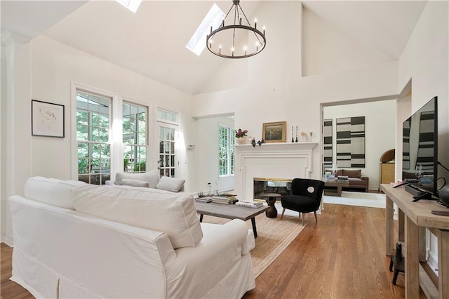 12160 Oak Hollow Way, Alpharetta, GA 30005 - living room featuring high vaulted ceiling, a chandelier, wood finished floors, and a glass covered fireplace