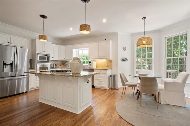 12160 Oak Hollow Way, Alpharetta, GA 30005 - kitchen featuring appliances with stainless steel finishes, tasteful backsplash, ornamental molding, white cabinetry, and a kitchen breakfast bar