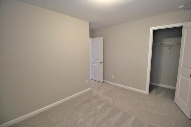 unfurnished bedroom with light carpet, a closet, and baseboards