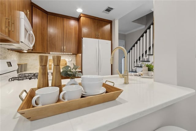 812 Dixie Ave NE, Atlanta, GA 30307 - kitchen with white appliances, backsplash, brown cabinets, light countertops, and recessed lighting