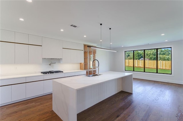 kitchen featuring gas cooktop, a center island with sink, dark hardwood / wood-style floors, and sink