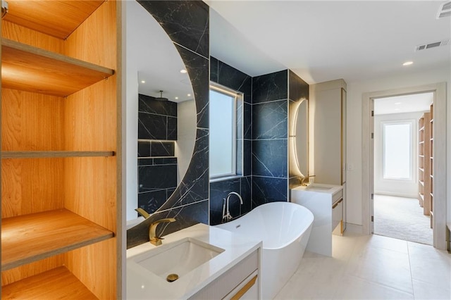 bathroom with a bathing tub, vanity, tile walls, and tile patterned flooring