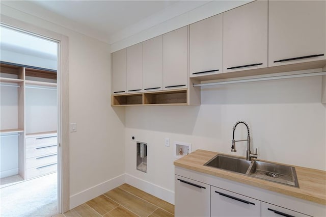 clothes washing area featuring electric dryer hookup, cabinets, sink, crown molding, and washer hookup