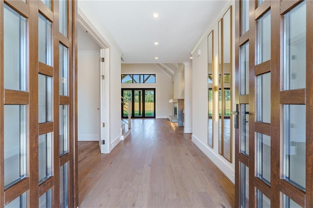 hallway with french doors, ornamental molding, and light wood-type flooring