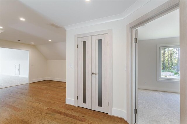 hall with light hardwood / wood-style floors, lofted ceiling, and crown molding