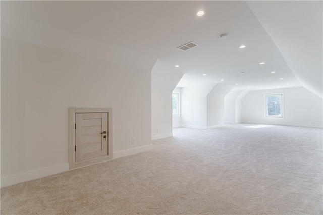 additional living space with a healthy amount of sunlight, light colored carpet, and lofted ceiling