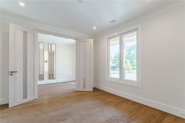 unfurnished room with light hardwood / wood-style flooring and crown molding