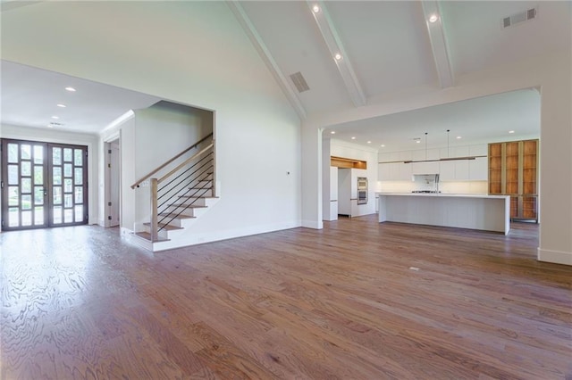 unfurnished living room with beamed ceiling, french doors, light hardwood / wood-style floors, and high vaulted ceiling