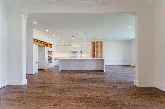 kitchen featuring white cabinets, a kitchen island with sink, dark wood-type flooring, and hanging light fixtures