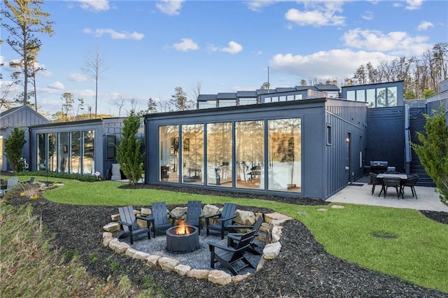 rear view of house with a patio, a lawn, and an outdoor fire pit