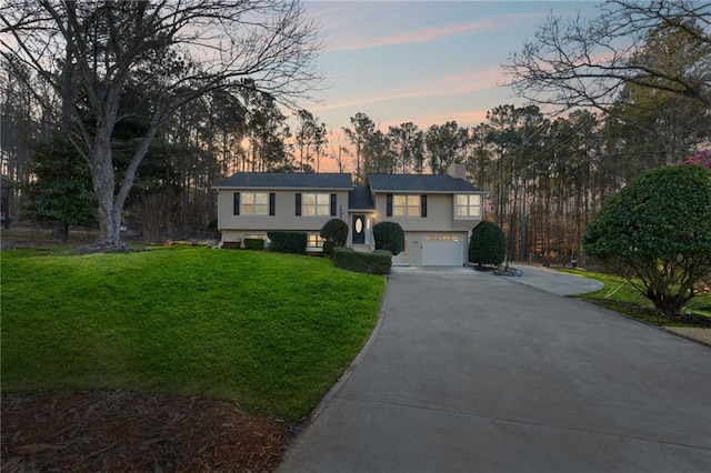 bi-level home featuring a front yard, a garage, and driveway