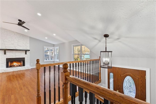 corridor featuring vaulted ceiling, an upstairs landing, recessed lighting, wood finished floors, and a textured ceiling