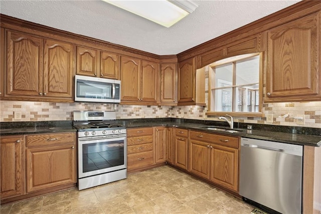 kitchen featuring a sink, backsplash, appliances with stainless steel finishes, and brown cabinetry