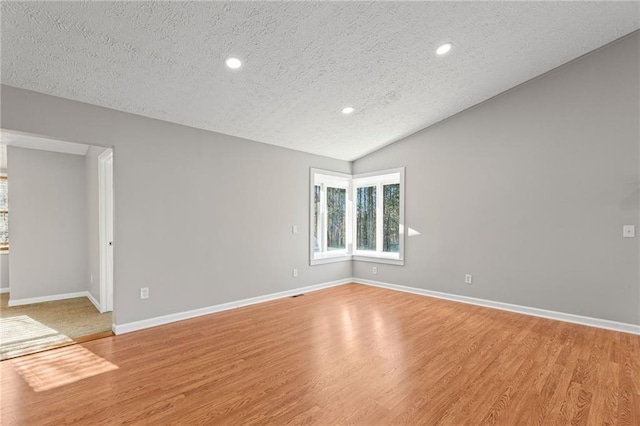 empty room with baseboards, recessed lighting, vaulted ceiling, light wood-style floors, and a textured ceiling