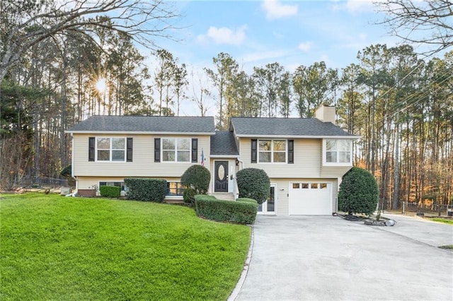 bi-level home featuring a front yard, concrete driveway, a garage, and a chimney