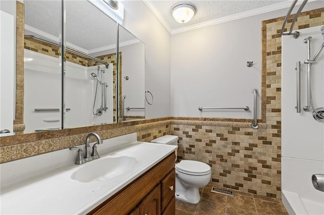 bathroom featuring toilet, ornamental molding, a textured ceiling, tile walls, and a shower