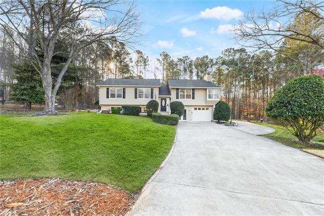 split foyer home featuring concrete driveway, an attached garage, a front lawn, and a chimney