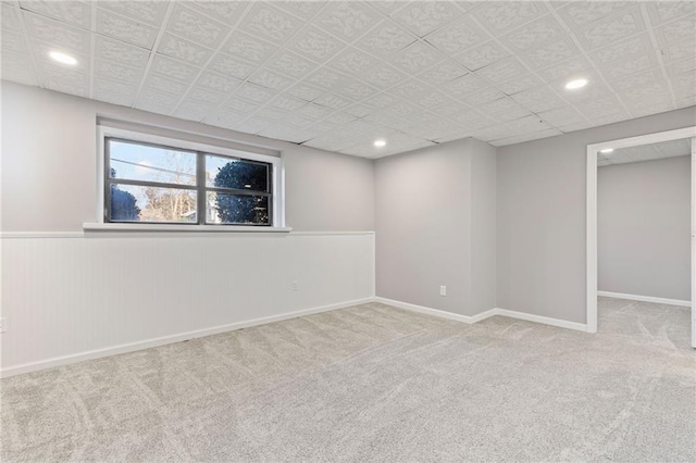 below grade area with carpet flooring, recessed lighting, baseboards, and wainscoting