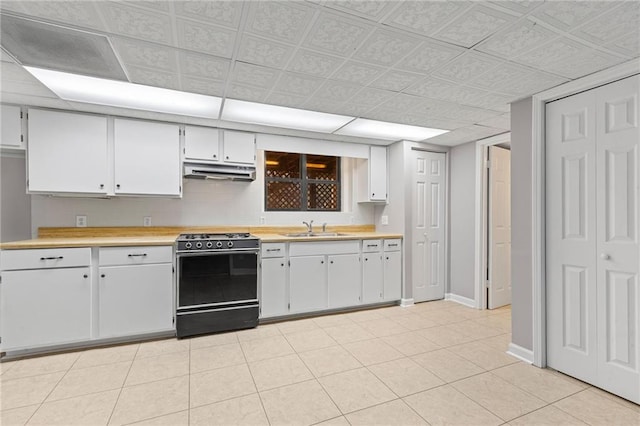 kitchen featuring gas stove, a sink, light countertops, white cabinets, and under cabinet range hood