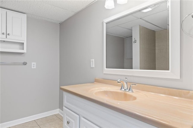 bathroom featuring tile patterned flooring, vanity, baseboards, and a drop ceiling