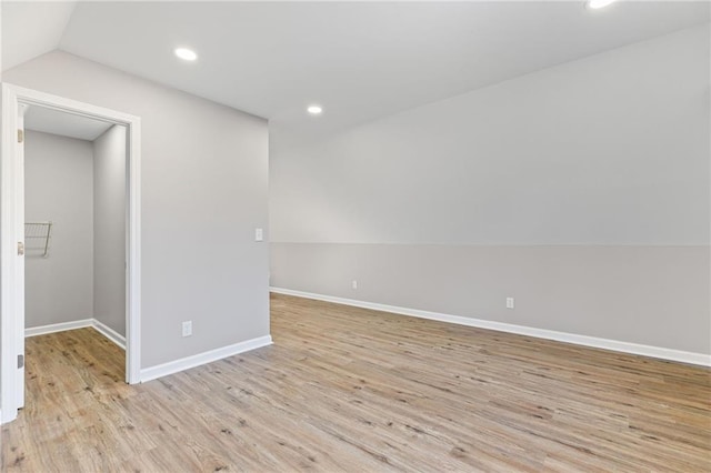 empty room with vaulted ceiling, recessed lighting, baseboards, and light wood finished floors