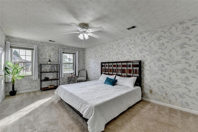 carpeted bedroom featuring wallpapered walls, baseboards, a textured ceiling, and ceiling fan