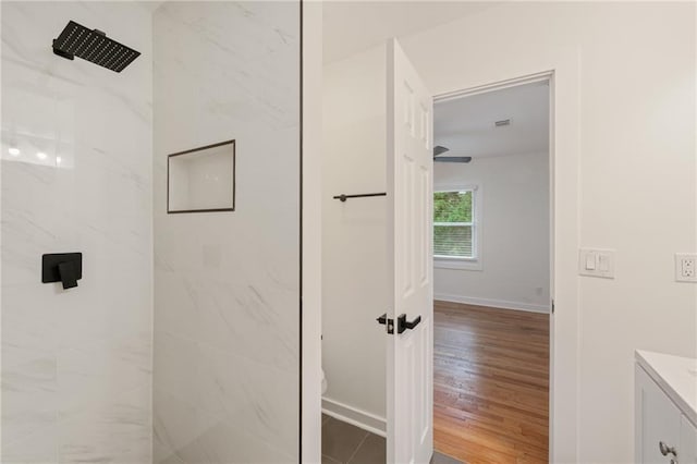 bathroom with tiled shower, vanity, and wood-type flooring