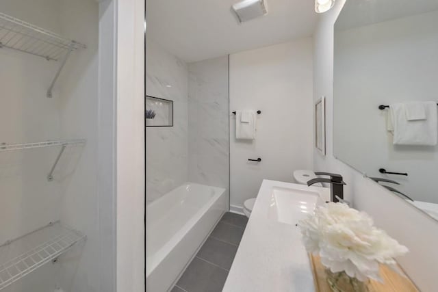 full bathroom with tiled shower / bath, tile patterned floors, toilet, and vanity