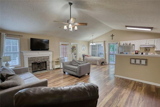 160 Riverbrooke Trl, Covington, GA 30016 - living room featuring a ceiling fan, wood finished floors, lofted ceiling, a textured ceiling, and a stone fireplace