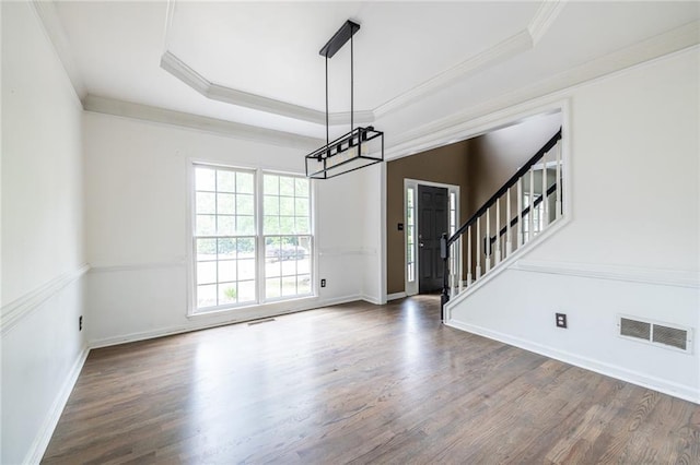 unfurnished room with a chandelier, wood finished floors, crown molding, a tray ceiling, and baseboards