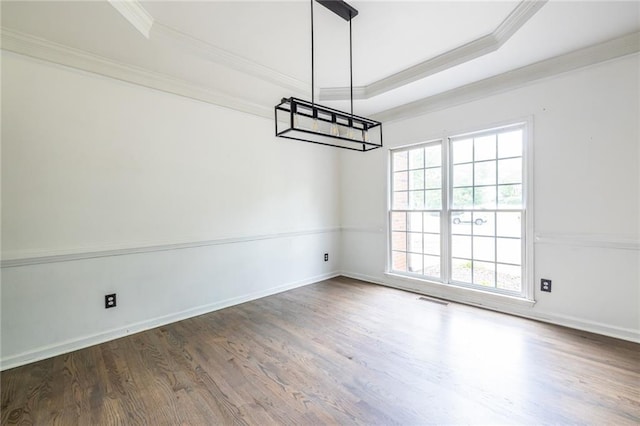 empty room featuring ornamental molding, wood finished floors, a tray ceiling, a chandelier, and baseboards