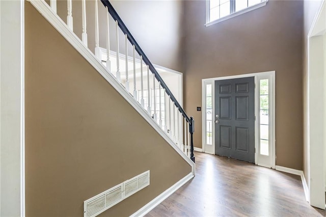 entryway featuring wood finished floors, a high ceiling, stairs, and baseboards