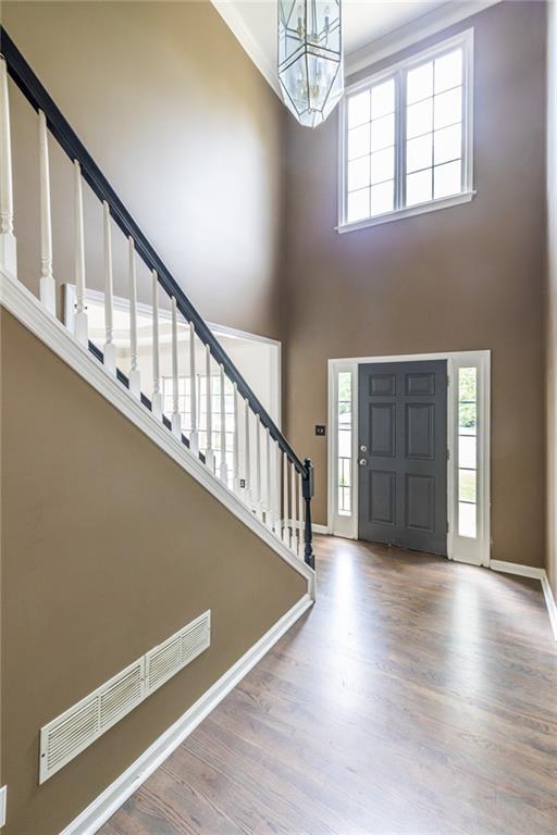 entryway with a chandelier, a towering ceiling, stairway, baseboards, and wood finished floors