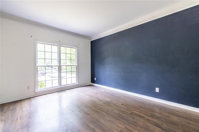 unfurnished room with healthy amount of natural light, ornamental molding, wood finished floors, and baseboards