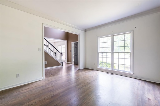 unfurnished room with plenty of natural light, stairs, wood finished floors, baseboards, and crown molding